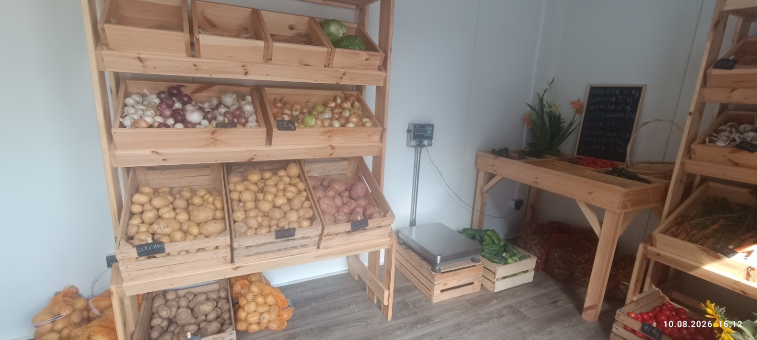 Warzywniak z drewnianymi skrzynkami warzyw i wagą przy stanowisku sprzedaży